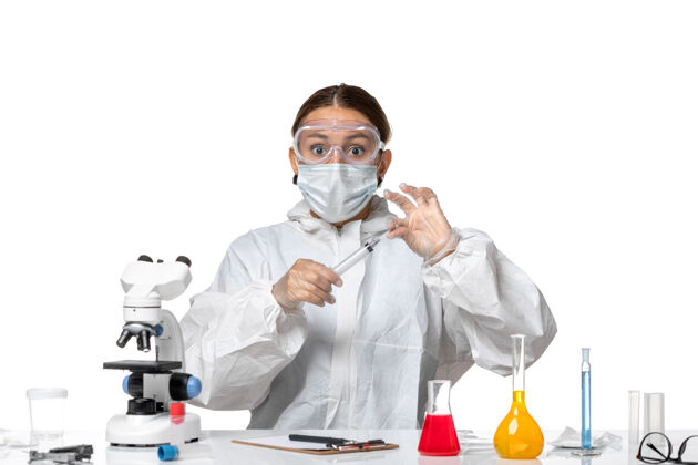 外套前视图：穿着防护服 戴着口罩的女医生正在注射一种白色背景的病毒药物——covid大流行防护人病毒