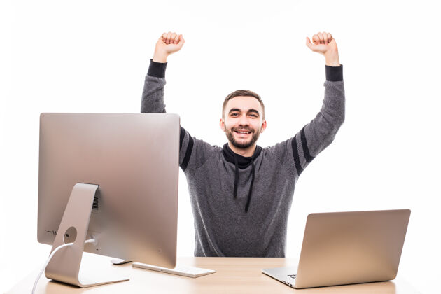 拳头一个年轻人举起拳头在白色的桌子旁用笔记本电脑和个人电脑桌子举起成功