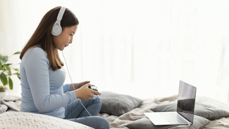 爱好戴着耳机玩电子游戏的女孩水平娱乐笔记本电脑