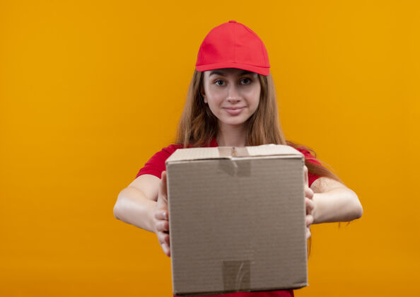 信心自信的年轻送货女孩在红色制服拉伸盒上孤立的橙色空间与复制空间复制红色女孩