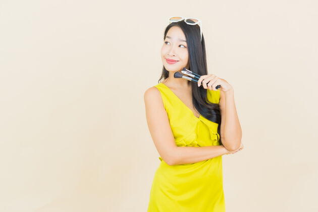 女孩在彩色墙上用化妆刷描绘美丽的亚洲年轻女子博客影响者女人