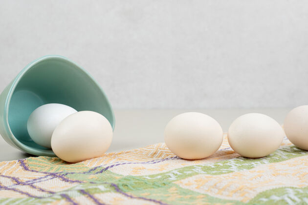 盘子几只新鲜的鸡蛋放在桌布上的蓝色盘子里未料理青色家禽