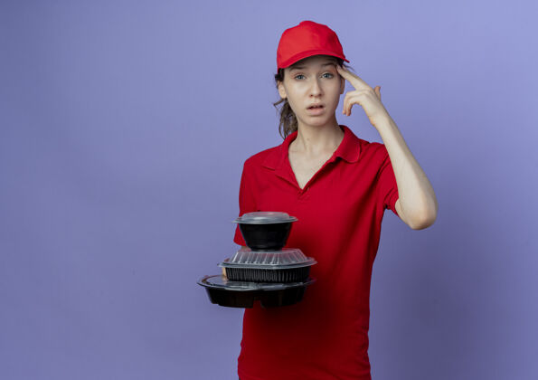 帽子受够了年轻漂亮的送货女孩穿着红色制服 戴着帽子拿着食物容器做手势孤立在紫色背景与复制空间紫色喂养
