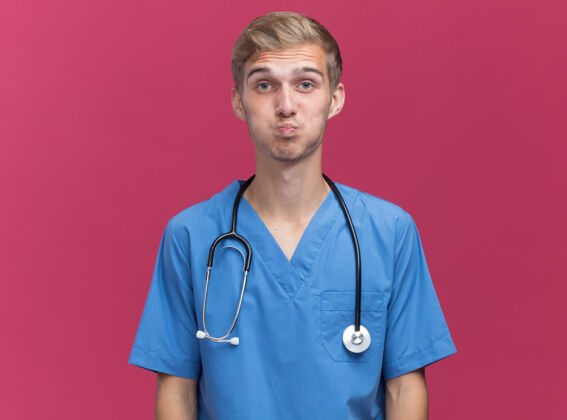 人年轻的男医生穿着医生制服 听诊器在粉红色的墙上显示亲吻的姿势手势人表情