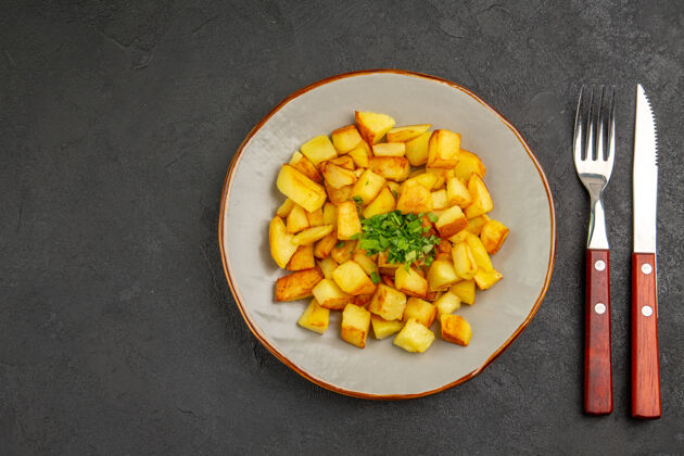 法国美味的炸土豆在黑暗的表面与绿色盘子里俯瞰食物谷物薯条