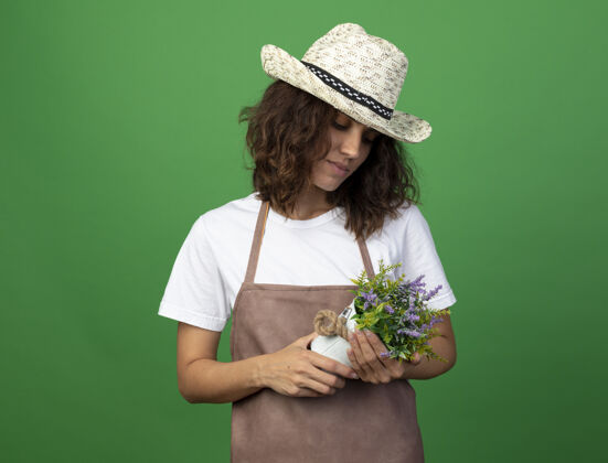 花想着穿着制服的年轻女园丁戴着园艺帽拿着花盆看花儿女人女人成人