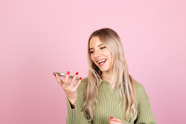 短信粉色墙上穿着休闲毛衣的漂亮欧洲女人电话显示华丽