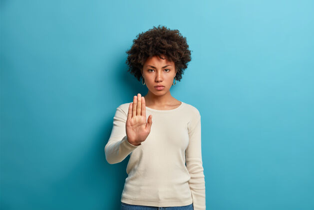 美国年轻严肃的黑皮肤女人显示停止标志禁止标志手掌向前严重防御显示