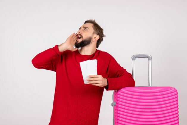 球员正面图：年轻男性 带着粉红色的包 手持机票 在白色的墙壁上航行 飞行 彩色旅行 旅游度假的照片机票肖像年轻男性