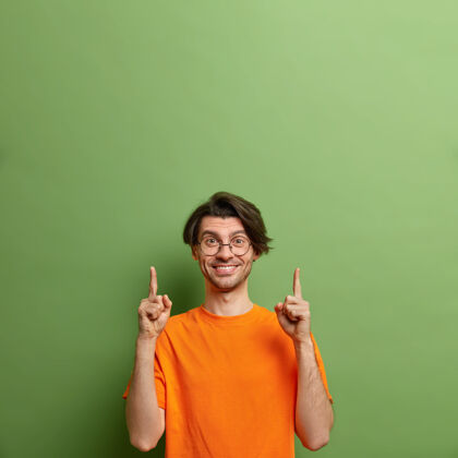 绿色工作室拍摄了一个快乐的欧洲男人 脸上没有刮胡子 表情积极 在空旷的空间里向上指欢呼肖像请