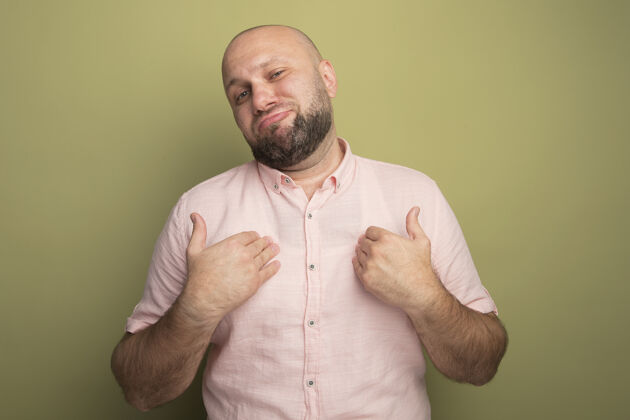 粉色一个穿着粉色t恤的中年秃头男人指着自己被隔离在橄榄绿上绿色橄榄色不愉快