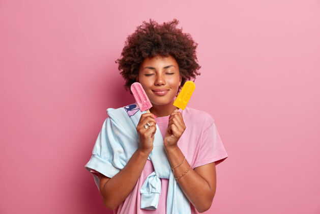 冰棒一位美籍黑人妇女闭着眼睛站着 手里拿着两个冰淇淋姿势食物时尚