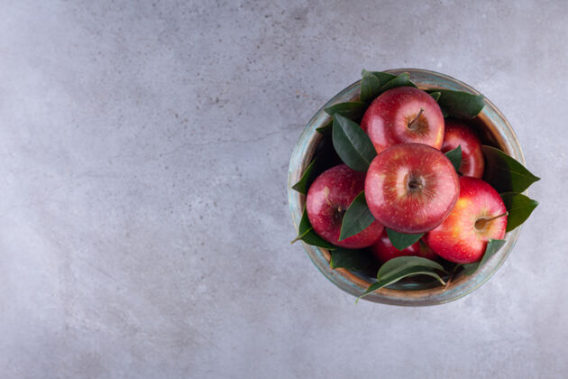 物体成熟的红苹果 叶子放在一个放在石头背景上的碗里食物生的生动