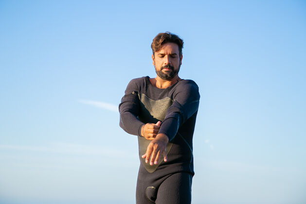 冲浪专注的运动员穿上潜水衣在海边冲浪海滩站立袖子