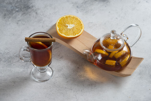 橙子一个装茶和橙子片的玻璃茶壶棕色杯子液体