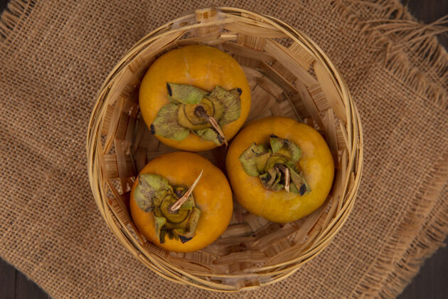 衣服木桌上的布袋上的桶上有机柿子水果的俯视图袋食品柿子