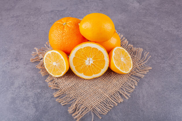 成熟整个和切片的橙色水果与新鲜柠檬放在麻布表面水果柠檬柑橘