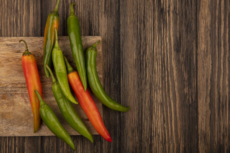 空间新鲜的五颜六色的辣椒在一个木制厨房板上的木制背景与复制空间隔离顶视图蔬菜板木材