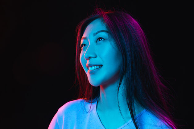 惊人亚洲年轻女性肖像在黑暗的霓虹灯墙壁上的人类情感的概念面部表情青年销售广告人青年辉光