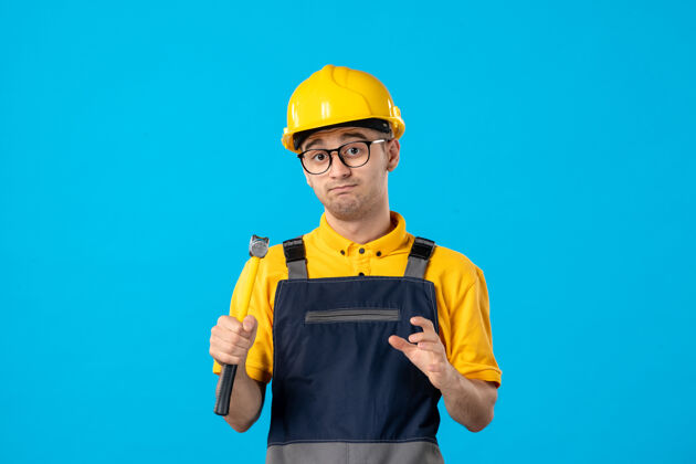 建筑正面图：男建筑工人穿着制服 戴着蓝色锤子的头盔工程师承包商修理工