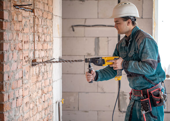 承包商勤杂工在用打孔器钻墙的过程中白专业年轻