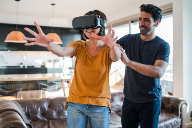 创新一对年轻夫妇在家里玩游戏 戴着虚拟现实眼镜玩游戏爱好一起游戏