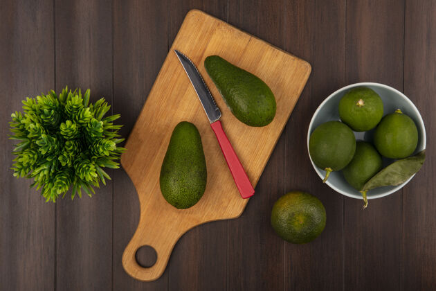 膳食顶视图明亮的绿色鳄梨在一个木制的厨房板上 刀子和柠檬放在一个碗里 橘子孤立在一个木制的背景上食物健康顶部