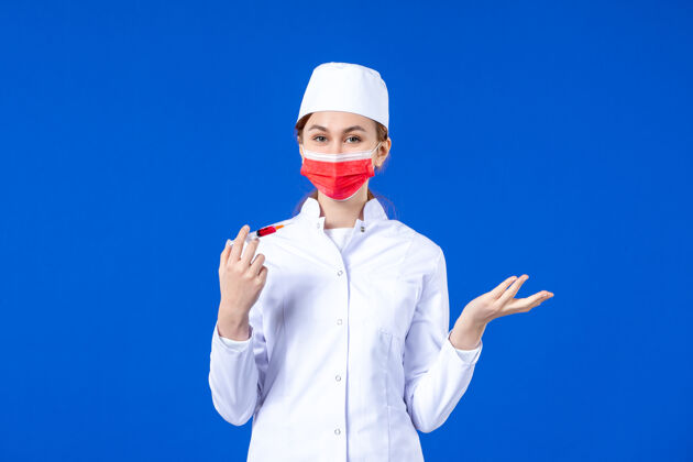 男人正面图：身穿白色医疗服的女护士 戴着红色面罩 手上拿着蓝色针剂疾病注射女护士