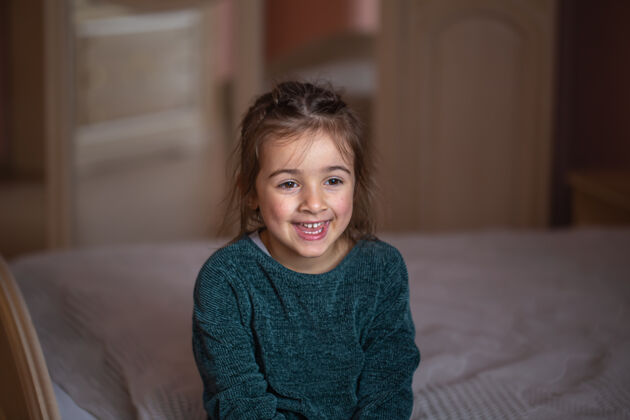 肖像床上一个小女孩在房间里的特写肖像 背景模糊脸青年室内