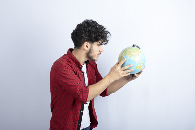 行星大胡子男人拿着地球仪靠着白墙的照片人孤独世界