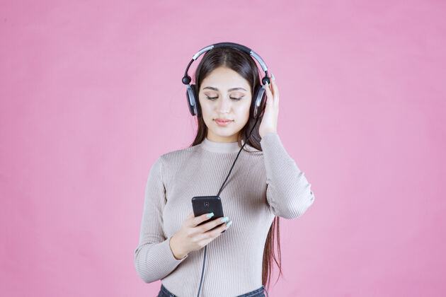 人类戴着耳机在智能手机前放音乐的女孩姿势女性单身