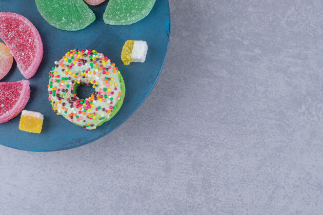 甜点在大理石表面的蓝色木板上放着一捆果酱和甜甜圈糖果顶部美味