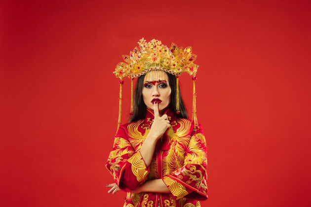 中国中国传统的优雅女子在摄影棚的红色背景美丽的女孩穿着民族服装中国新年 优雅 优雅 表演者 表演 舞蹈 女演员 服装的概念民族优雅艺妓