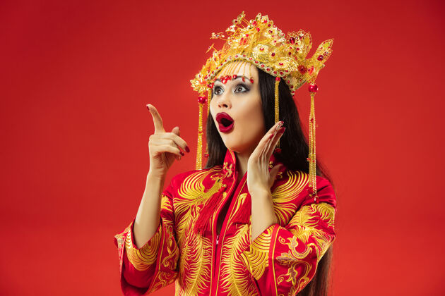 文化中国传统的优雅女子在摄影棚的红色背景美丽的女孩穿着民族服装中国新年 优雅 优雅 表演者 表演 舞蹈 女演员 服装的概念中国人中国服饰