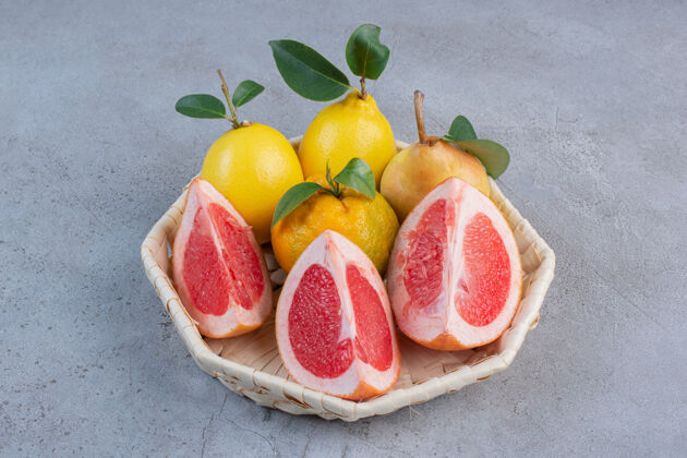 美味雪梨和葡萄柚片放在大理石背景上的白色篮子里美味新鲜风味
