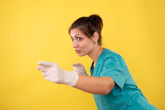 休闲前视图黄色背景上戴着医用手套的女医生视图护士黄色