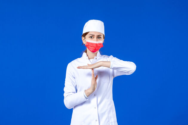 防护服正面图身着医疗服的年轻护士 蓝色墙上戴着红色防护面具时间病毒面罩