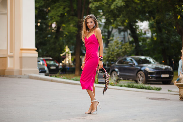 美丽优雅迷人的女人穿着粉色性感夏装 手拿手袋走在街上现代年轻潮流