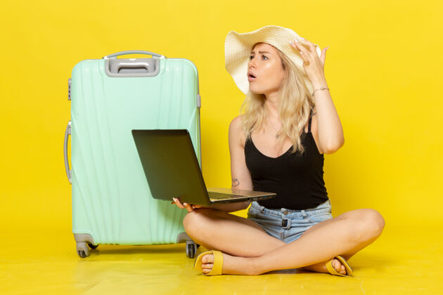 微笑正面图年轻女性在黄色书桌上使用笔记本电脑女孩旅行旅行旅行旅行旅行太阳视图书桌漂亮