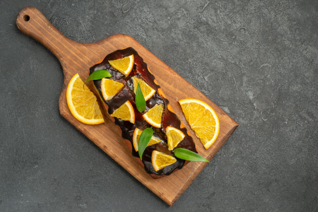 板上图：美味的蛋糕装饰着橘子和巧克力 放在黑桌子的砧板上美味蛋糕巧克力餐厅