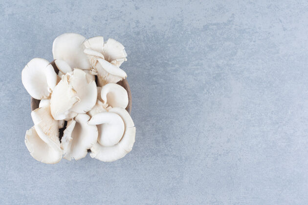许多一碗新鲜的牡蛎蘑菇 灰色背景餐桌蔬菜木头