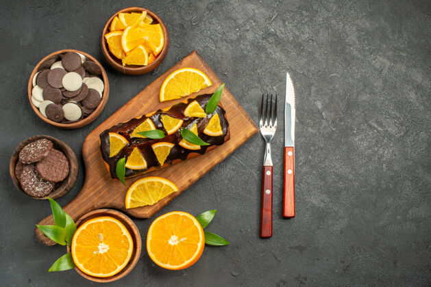 切割在木制砧板上放软蛋糕 在深色的桌子上切橘子和叶子饼干深色突出显示木板