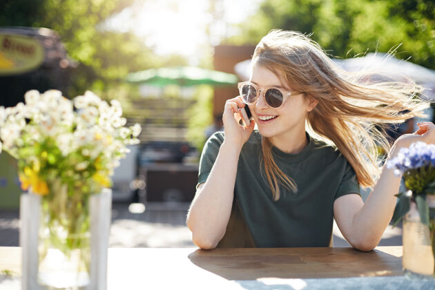 柠檬水年轻的金发女郎戴着眼镜和朋友或情人在社交媒体上用粉色手机交谈的照片咖啡馆员工电话