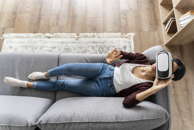虚拟现实坐在沙发上玩虚拟现实耳机的女人增强现实虚拟现实家庭