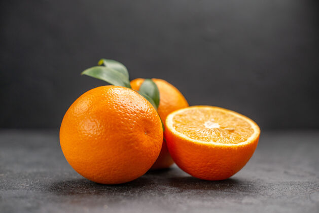 封闭黑暗的桌子上新鲜的整片柠檬和切片柠檬的特写镜头甜橙柑橘柑橘