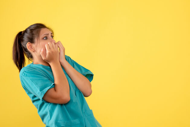 肖像正面图黄色背景上穿着医用衬衫 表情惊恐的女医生医疗护士黄色