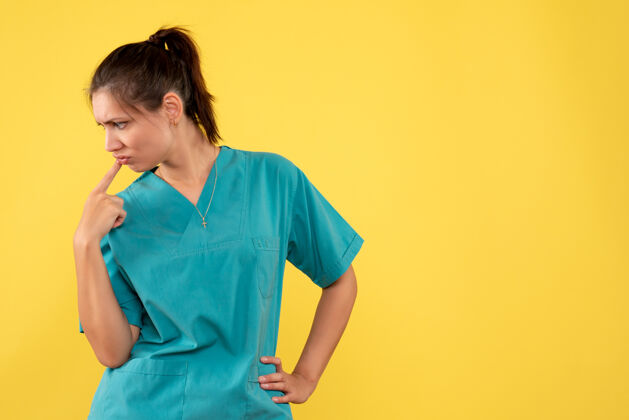 思考正面图穿着医用衬衫的女医生在黄色背景上紧张地思考健康女医生视图