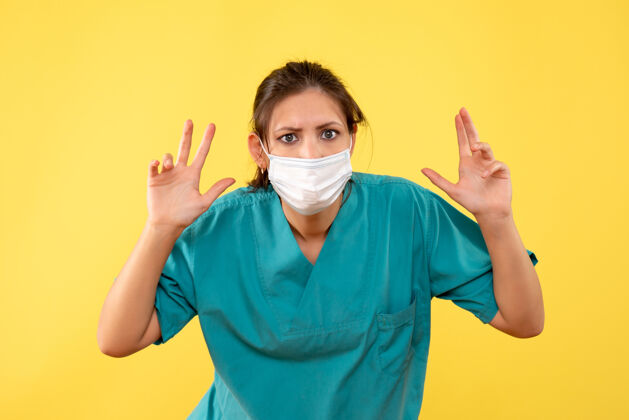 人正面图黄色背景上穿着医用衬衫和无菌口罩的女医生视图医疗衬衫