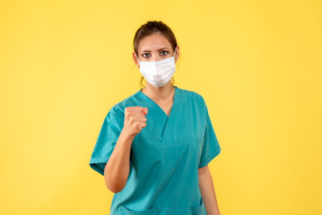 成人前视图黄色背景上穿着医用衬衫和面罩的女医生病毒衬衫正面