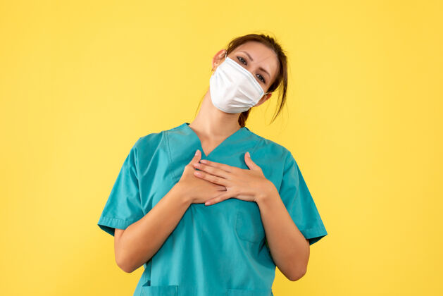视图正面图黄色背景上穿着无菌口罩医用衬衫的女医生健康女医生衬衫